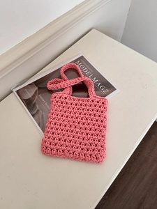 Close-up of pink handmade crochet tote bag with textured knit pattern and top handles