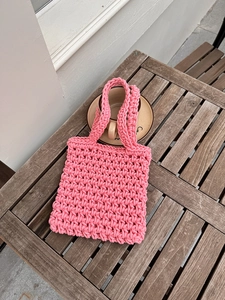 Detailed view of pink handmade crochet tote bag with hollow woven texture on a wooden table