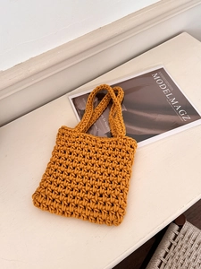 Detail of hand-woven ginger hollow mesh bag texture on minimalist wooden surface