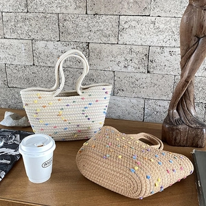 Handwoven cotton rope tote bags with colorful pom-poms and round handles in two tones