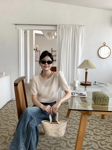 Detail of a beige woven cotton tote bag paired with a casual textured top and jeans