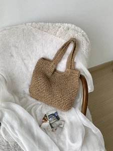 Detail of hand-woven straw tote bag with fine texture on a soft white fur background