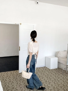 Detail of woven cotton tote bag paired with white puff sleeve top and denim jeans