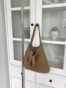 Detail of handcrafted brown woven straw tote bag texture hanging on a vintage cabinet