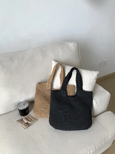 Detail of beige and black woven straw tote bags in a minimalist home setting