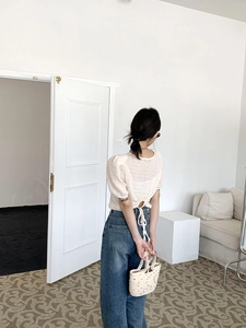 Detail of white puff sleeve top with open back tie design and blue denim jeans