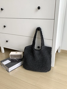 Detailed view of black crochet woven tote bag with hollow texture in a cozy home setting
