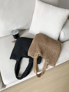 Detailed texture of large straw woven tote bags in black and natural beige on a sofa
