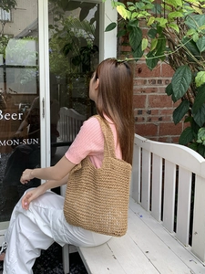 Detail of hand-woven straw tote bag showing large capacity and integrated handle