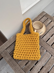 Handmade yellow crochet tote bag with woven texture on a wooden table for summer beach style