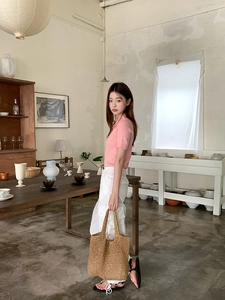 Close-up of a large capacity brown straw tote bag styled with a summer outfit