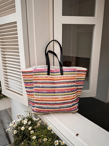 Large striped straw tote bag with multi-color patterns and black leather handles for summer