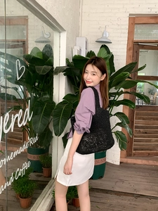 Fashionable black woven shoulder tote bag styled with casual summer outfit outdoors
