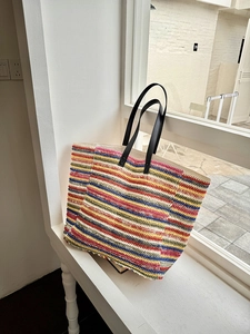 Detail of colorful striped woven tote bag with premium black leather handles and textures