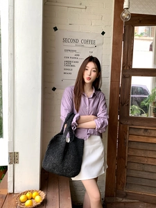 Fashionable black straw woven tote bag styled with a casual purple shirt and white skirt