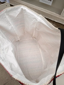 Large woven tote bag with white fabric lining and tricolor braided trim detail