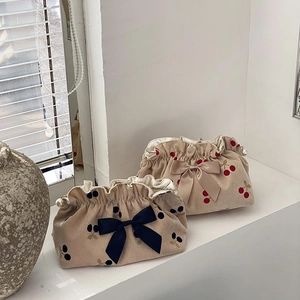 Corduroy pouch detail with cherry pattern, large bow, and elegant pearl pendant