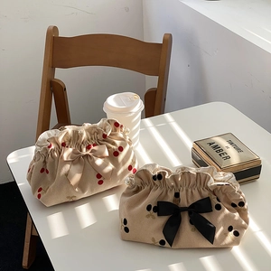 Detail of corduroy makeup bags with cherry embroidery, satin bows and pearl charms