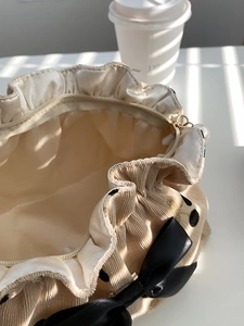 Detail of beige corduroy pouch with polka dots, satin lining and pearl zipper charm