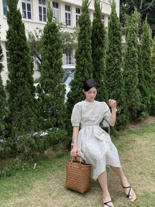Detailansicht einer braunen Vintage-Flechtkorbtasche kombiniert mit einem Blumenkleid