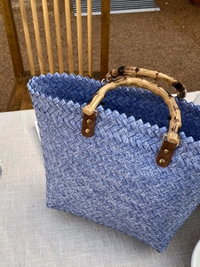 Detail der geflochtenen Korbtasche mit Bambusgriffen und blau-weißer Textur