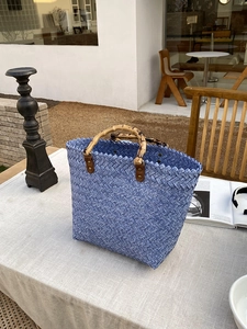 Detail of blue woven tote bag featuring natural bamboo handles and retro rivet connectors