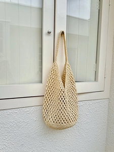 Detailed close-up of hollow crochet texture on this beige straw tote holiday bag