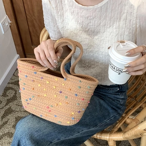 Handwoven cotton cord tote bag featuring colorful pom-poms and dual top handles