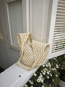 Detail of hollow woven shoulder bag with floral pattern on a sunny summer windowsill