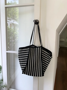 Close-up of black and white striped knit tote bag showing woven texture and soft shadows