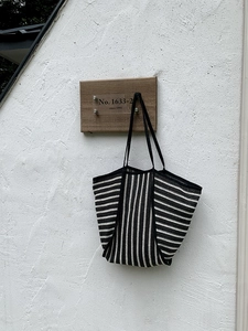 Close-up of black and white striped woven tote bag with durable double handles