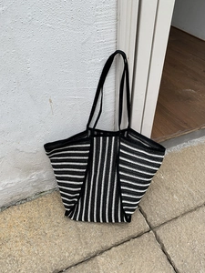 Detail of black and white striped woven tote bag with durable long handles and textured finish
