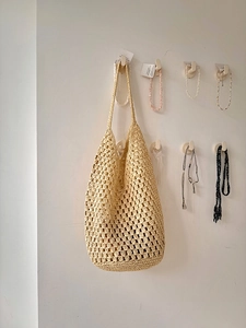 Close-up of beige woven tote bag showing crochet hollow mesh structure and soft cotton texture