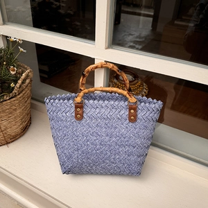 Detail of blue and white woven tote bag with bamboo handle on a window sill
