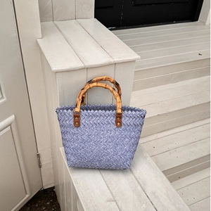 Detail of blue and white woven tote bag featuring a vintage bamboo handle and leather tabs
