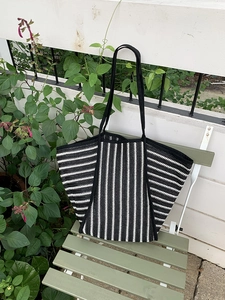 Detail shot of the black and white striped knit texture on a large woven tote bag