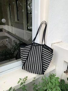 Detail of black and white striped knit tote bag with woven texture on white window sill