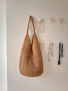 Close-up of hollow straw shoulder bag showing intricate hand-woven mesh texture in ginger brown