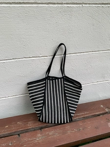 Detail of black and white striped crochet knit tote bag resting on a wooden bench