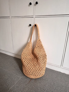 Detailed view of the hollow crochet weave texture and light brown fiber on a beach hobo bag