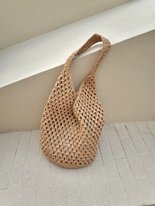 Detailed view of hollow mesh weave texture on khaki raffia straw shoulder tote bag