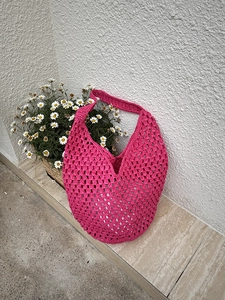 Detailed texture of fuchsia crochet tote bag with hollow woven mesh and sturdy wide handle