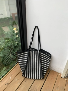 Macro detail of striped woven tote bag featuring dense texture and reinforced shoulder strap