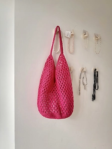 Close-up of the magenta woven hobo bag showing detailed crochet texture and hollow design