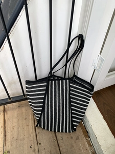 Close-up of black and white striped woven tote bag with durable braided shoulder straps
