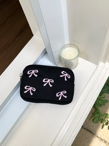 Close-up of black canvas storage pouch with pink embroidered bows and zipper