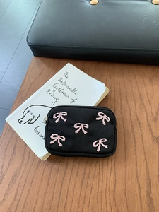 Detail of black canvas mini pouch featuring pink embroidered bows and silver zipper