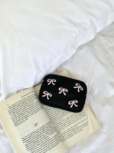 Detail shot of black canvas pouch with pink embroidered bows on vintage book