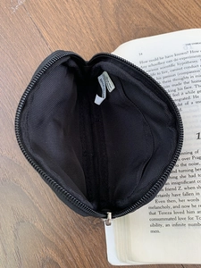 Black nylon mini coin purse with heart embroidery and zipper closure on a wooden desk