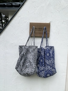 Detail of grey and blue paisley canvas tote bags with vintage prints and slim straps